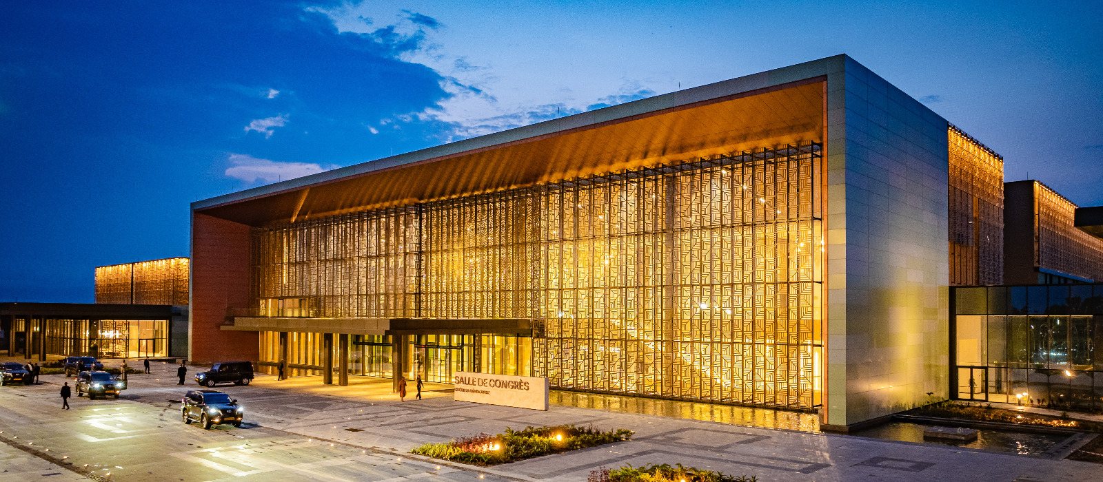 The Omar Bongo Ondimba Convention Center at dusk, its patterned facade lit from within